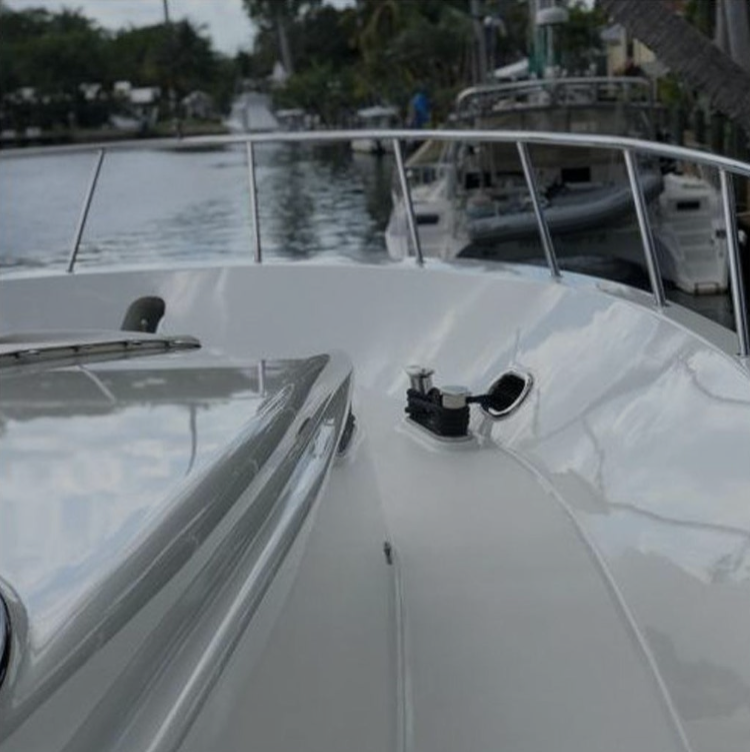 This image shows the bow of a well-maintained boat with a polished and shiny surface, reflecting the clear sky and surrounding environment. The boat’s clean finish highlights the smooth contours and reflects the light off the deck, indicating proper care and maintenance.