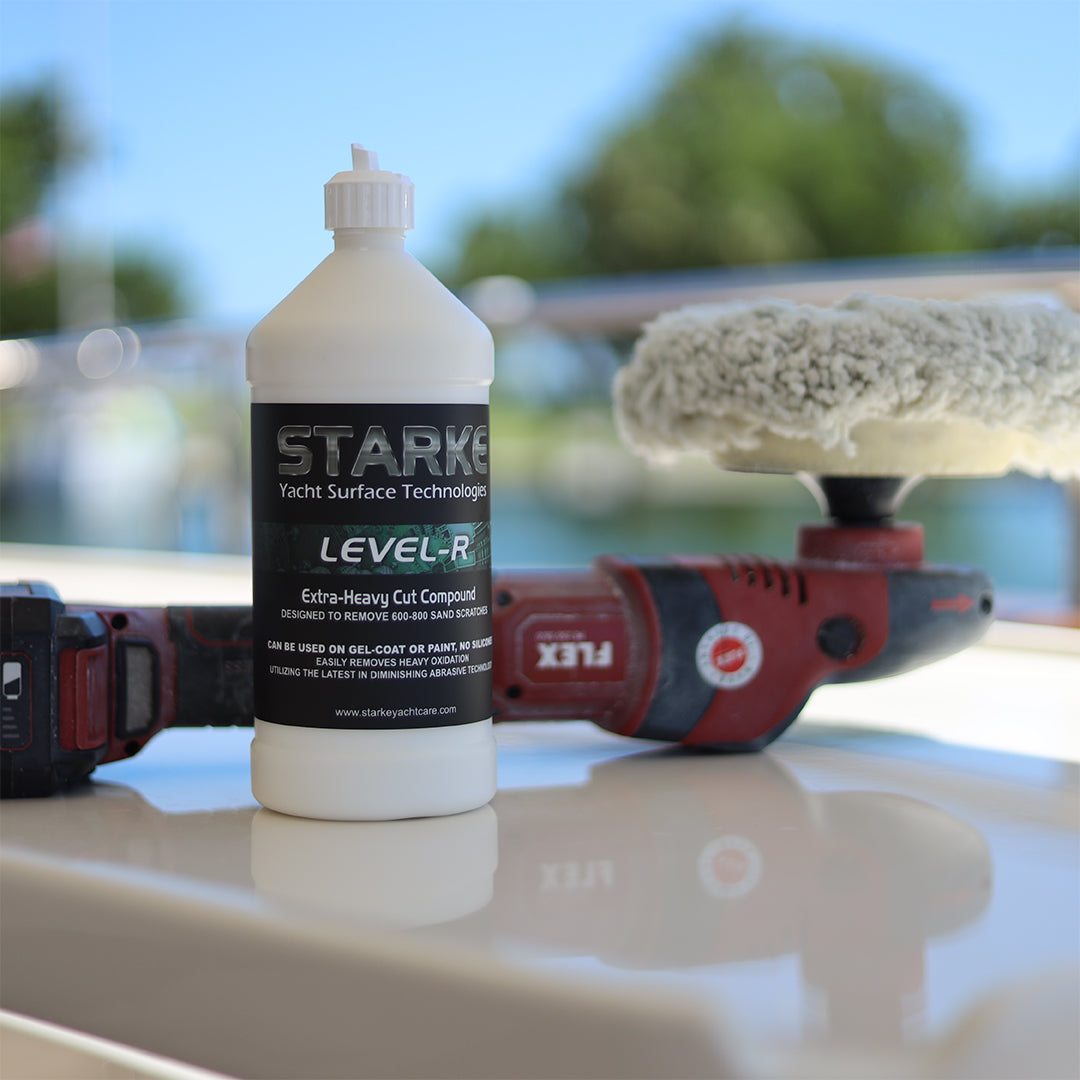 A bottle of Starke Level-R Extra-Heavy Cut Compound is placed on a work surface next to a polishing tool, with a foam pad visible. The product is designed to remove heavy sand scratches from gel-coat or paint.
