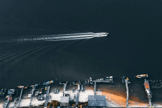 Aerial view of a boat cutting across open water near a marina, illustrating the impact of a well-maintained hull.