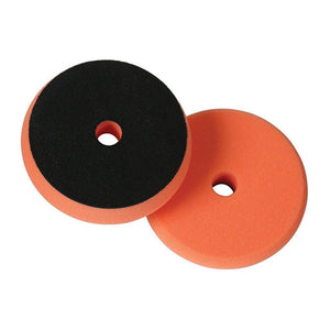 Dual-sided polishing pad with an orange foam surface and a black abrasive side, designed for efficient cleaning and polishing, featuring a central hole for attachment.